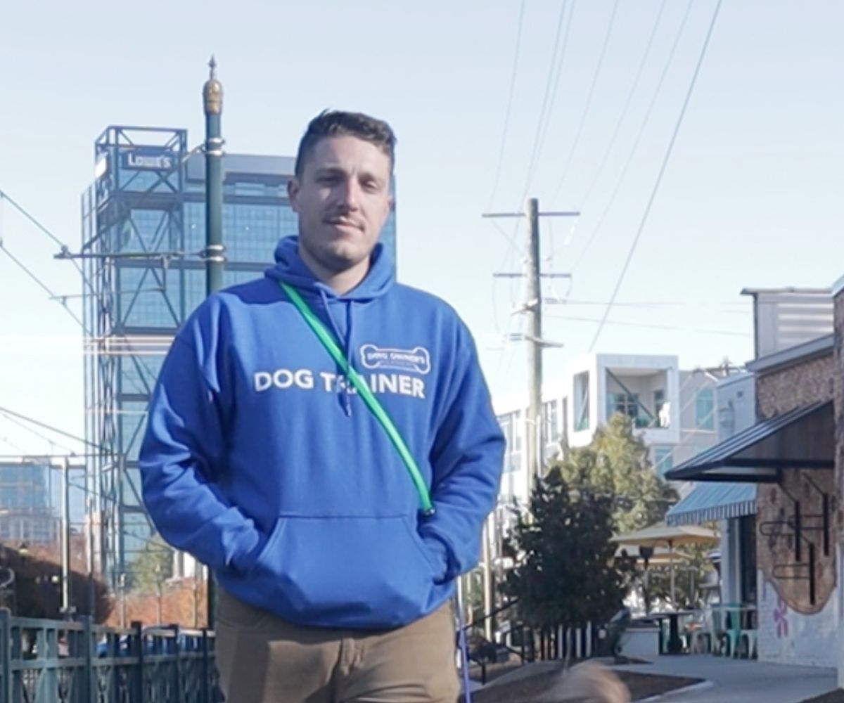 Dom Dog Trainer In Charlotte Nc Photo of Dom, a dog trainer in Charlotte, NC wearing a blue sweatshirt that says Dog Trainer