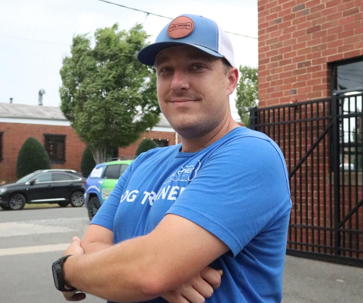 Photo of Dom, a dog trainer in Charlotte, NC wearing a blue t-shirt that says Dog Trainer