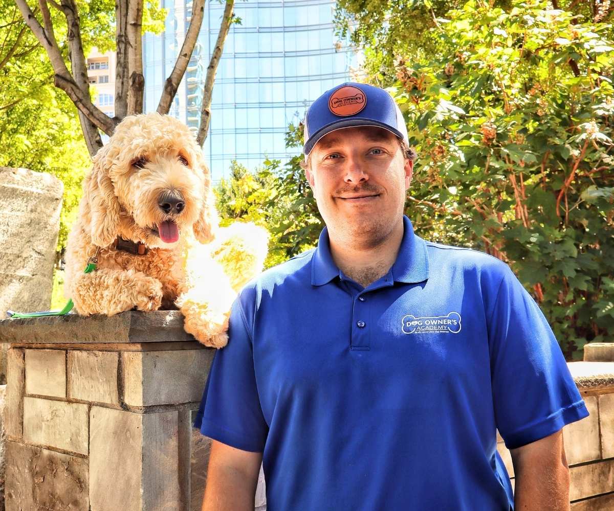 Dom Dog Owners Academy Trainer In Charlotte Nc Photo of Dom, a dog trainer in Charlotte, NC standing next to a white doodle